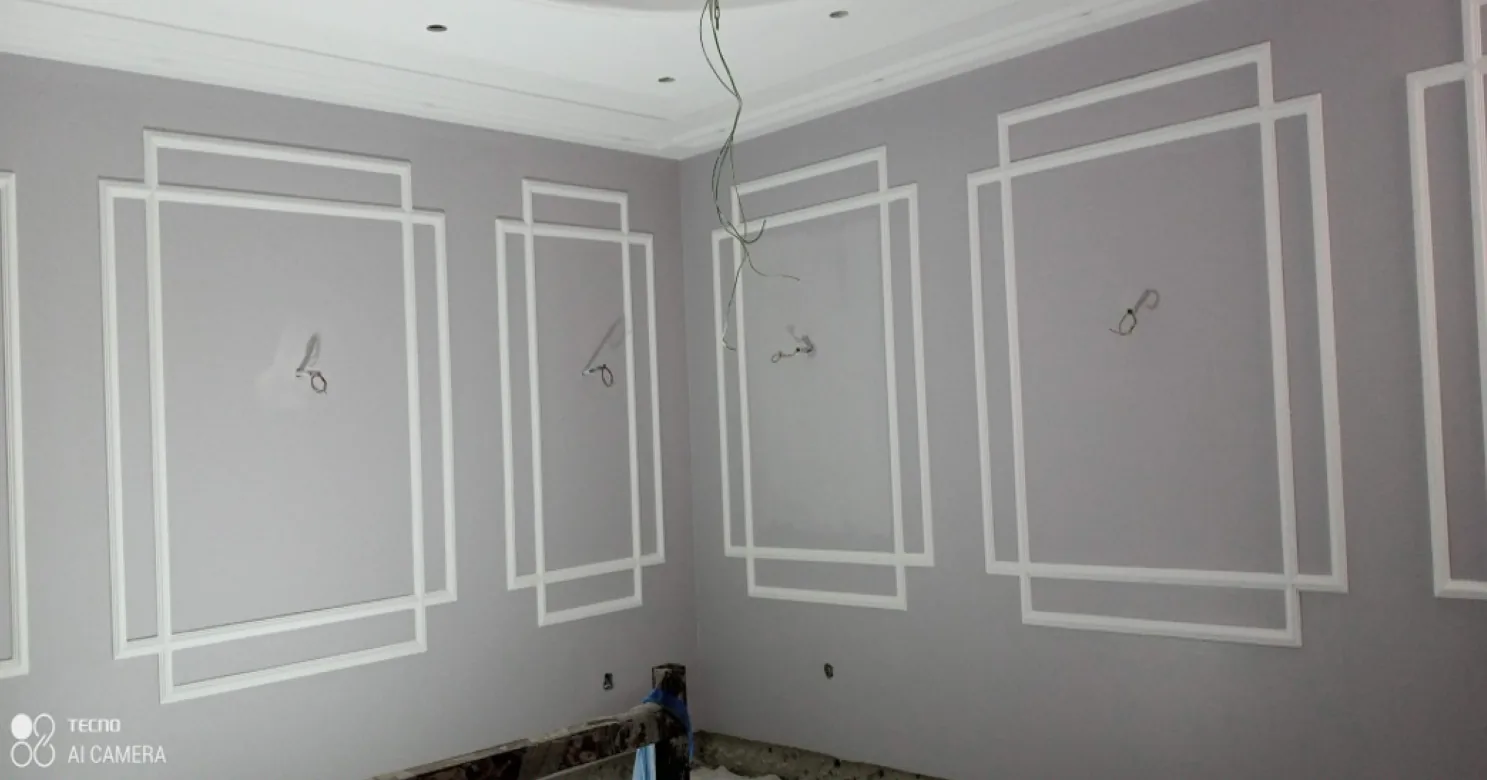 Lilac-grey room with white rectangular moulding frames on the walls, recessed downlight openings, and cable stubs at each panel.