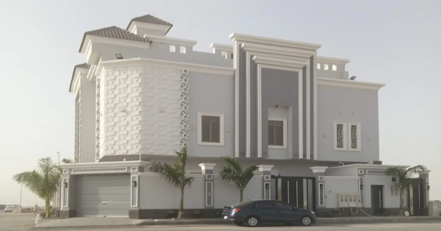 Grey and white villa corner with a textured white block bay, lattice screens, moulded cornices, palms and a parked dark car.