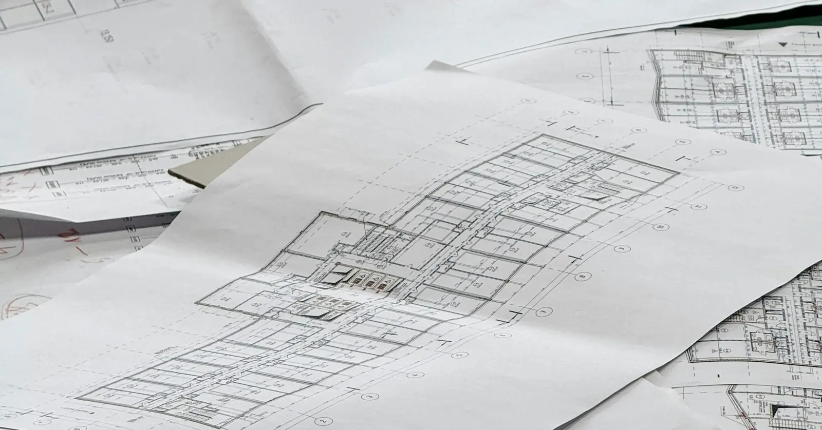 Several sheets of architectural floor-plan drawings spread across a table