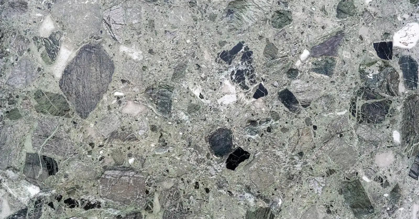 Close view of a polished stone conglomerate surface with large green-grey and black stone fragments